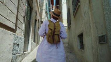 Sırt çantalı genç ve çekici bir turist seyahat ederken eski şehrin sokaklarında geziniyor, mimariye hayran, etrafa bakıyor. İtalya.