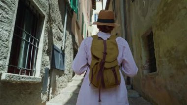 Sırt çantalı genç ve çekici bir turist seyahat ederken eski şehrin sokaklarında geziniyor, mimariye hayran, etrafa bakıyor. İtalya.