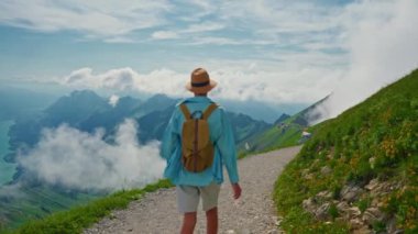Sırt çantalı yakışıklı delikanlı İsviçre 'de güzel gölün üstündeki dağın tepesinde seyahat ediyor. Arka planda güzel dağlarda Interlaken..