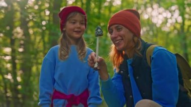 Bir anne ve sevimli küçük kızı ormanda büyük bir mantar buldular ve birlikte bakıyorlar, tatilde boş zamanlarının tadını çıkarıyorlar. Çocuk çok mutlu. Mutlu aile.