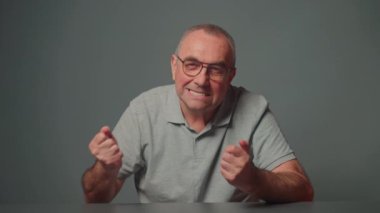 Emekli bir adam elleriyle güç ve dayanıklılık göstergesi gösterir..