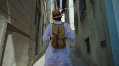 Sırt çantalı genç ve çekici bir turist seyahat ederken eski şehrin sokaklarında geziniyor, mimariye hayran, etrafa bakıyor. İtalya.