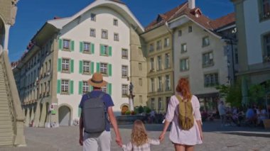 Bern, İsviçre, 29 Temmuz 2024: Sırt çantalı bir anne, genç bir oğlan ve küçük bir kız eski Bern kasabasını geziyor. Aile seyahati.