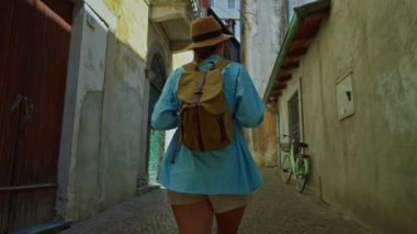 Sırt çantalı genç ve çekici bir turist seyahat ederken eski şehrin sokaklarında geziniyor, mimariye hayran, etrafa bakıyor. İtalya.
