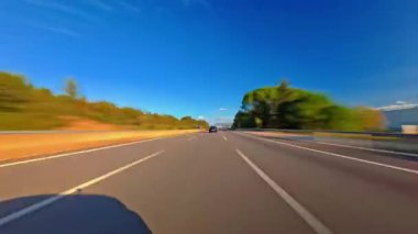 Otoyol boyunca sürüşün zamanı. Yolun ve çevrenin ön manzarası. Ağaçlar yolun iki tarafına da uzanıyor. Hızlı araba hipersürati. Yolculuk konsepti bir çeşit konsol kamerası POV 'u..