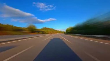 Otoyol boyunca sürüşün zamanı. Yolun ve çevrenin ön manzarası. Ağaçlar yolun iki tarafına da uzanıyor. Hızlı araba hipersürati. Yolculuk konsepti bir çeşit konsol kamerası POV 'u..