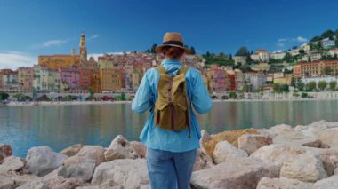 Menton, Fransa 'da arka plandaki renkli evlerde yürüyen güzel bir kadın. Cote dAzur, Fransa.