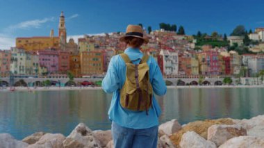 Menton, Fransa 'da arka plandaki renkli evlerde yürüyen güzel bir kadın. Cote dAzur, Fransa.