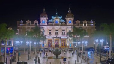 Monaco, Monte-Carlo. Casino Monte-Carlo 'nun ünlü meydanı, alacakaranlıkta eğlence gecesi aydınlatması, lüks arabalar, turistler. Zaman Uygulaması.