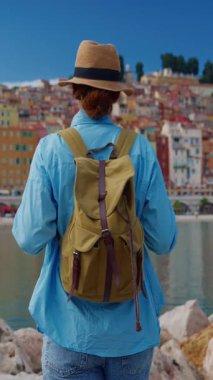 Menton, Fransa 'da arka plandaki renkli evlerde şapkalı güzel bir kadın duruyor. Cote dAzur, Fransa.