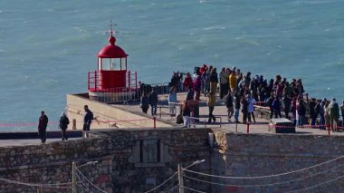 Portekiz, Nazare, 20 Şubat 2025: İnsanlar deniz fenerinde duruyor ve Nazare Portekiz 'in en ünlü yerinde sörfçülerin dev dalgaları fethetmelerini izliyorlar..