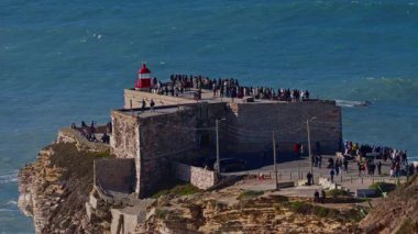 Portekiz, Nazare, 20 Şubat 2025: İnsanlar deniz fenerinde duruyor ve Nazare Portekiz 'in en ünlü yerinde sörfçülerin dev dalgaları fethetmelerini izliyorlar..