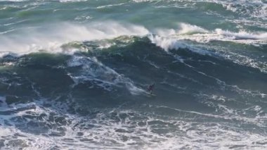 Sörfçü büyük dalgalarda sörf yapıyor. Büyük dalga sörfü. Nazare, Portekiz.