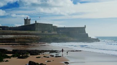 Portekiz, Carcavelos sahilinden deniz feneri kulesi olan Aziz Julian Kalesi. Carcavelos 'taki Atlantik okyanus dalgaları plajı.