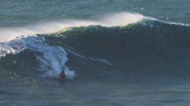 Onu jet ski ile büyük bir dalgaya götüren eskortlu bir sörfçü. Olağanüstü bir spor. Nazare, Portekiz.