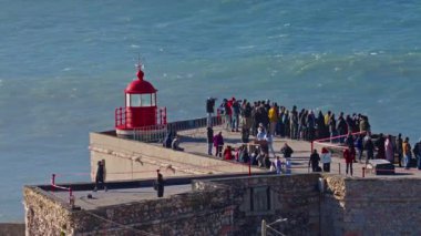 Portekiz, Nazare, 20 Şubat 2025: İnsanlar deniz fenerinde duruyor ve Nazare Portekiz 'in en ünlü yerinde sörfçülerin dev dalgaları fethetmelerini izliyorlar..