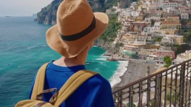 Şapkalı ve sırt çantalı bir bayan turist Amalfi kıyısındaki ünlü İtalyan turist kasabası Positano 'da yürüyor. Positano, İtalya.