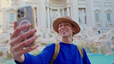 Roma 'da sırt çantalı ve şapkalı bir turist Trevi Çeşmesi' nde selfie çekiyor. Roma, İtalya 'da seyahat.