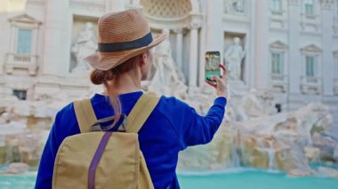 Roma 'da sırt çantalı ve şapkalı bir turist Trevi Çeşmesi' nin videosunu çekiyor. İtalya, Roma 'da seyahat ediyor..