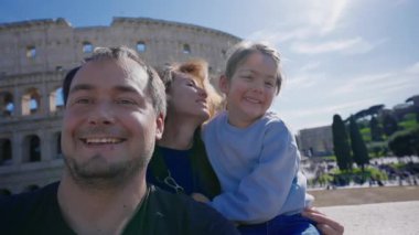 Roma 'da arka planda Colosseum' la fotoğraf çektiren ve kameraya gülümseyen bir aile. Roma, İtalya 'da turistler.