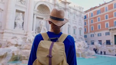 Şapkalı ve sırt çantalı bir kadın turist Trevi Çeşmesi 'nin önüne geliyor. Roma, İtalya 'yı gezen güzel bir kadın..