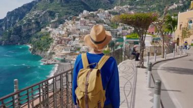 Şapkalı ve sırt çantalı bir bayan turist Amalfi kıyısındaki ünlü İtalyan turist kasabası Positano 'da yürüyor. Positano, İtalya.