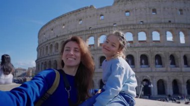 Bir anne ve küçük kızı Roma 'da Colosseum' un önünde selfie çekerken kameraya gülümsüyor. Roma, İtalya 'da turistler.