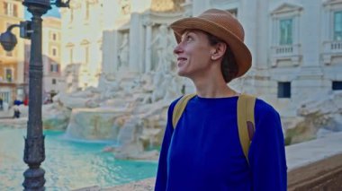 Şapkalı ve sırt çantalı bir kadın turist Trevi Çeşmesi 'nin önüne geliyor. Roma, İtalya 'yı gezen güzel bir kadın..