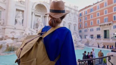 Şapkalı ve sırt çantalı bir kadın turist Trevi Çeşmesi 'nin önüne geliyor. Roma, İtalya 'yı gezen güzel bir kadın..