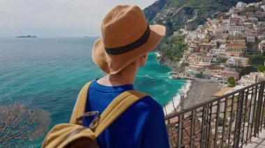 Şapkalı ve sırt çantalı bir bayan turist Amalfi kıyısındaki ünlü İtalyan turist kasabası Positano 'da yürüyor. Positano, İtalya.