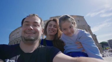 Roma 'da arka planda Colosseum' la fotoğraf çektiren ve kameraya gülümseyen bir aile. Roma, İtalya 'da turistler.