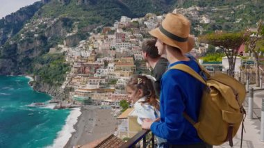 Amalfi Sahili 'nde tatilde olan dört kişilik bir aile, İtalya' nın ünlü turistik kasabası Positano 'nun manzarasının tadını çıkarıyor..