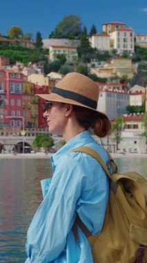 Menton, Fransa 'da arka plandaki renkli evlerde şapkalı güzel bir kadın duruyor. Cote dAzur, Fransa.