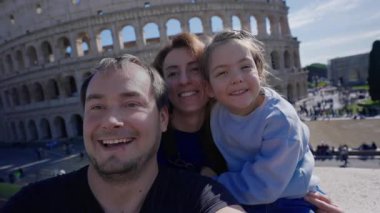 Roma 'da arka planda Colosseum' la fotoğraf çektiren ve kameraya gülümseyen bir aile. Roma, İtalya 'da turistler.