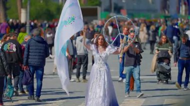 Roma, İtalya, 29.04.2025: Beyaz elbiseli, elinde bayrak ve barış sembolü olan bir kız, güneşli bir günde Roma 'nın orta caddesinde barış çağrısı yaparak halkı barışa çağırıyor..