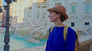 Şapkalı ve sırt çantalı bir kadın turist Trevi Çeşmesi 'nin önüne geliyor. Roma, İtalya 'yı gezen güzel kadın, 29.04.2025.