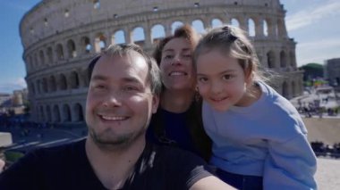 Roma 'da arka planda Colosseum' la fotoğraf çektiren ve kameraya gülümseyen bir aile. Roma, İtalya 'da turistler.