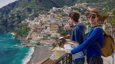 Amalfi Sahili 'nde tatilde olan dört kişilik bir aile, İtalya' nın ünlü turistik kasabası Positano 'nun manzarasının tadını çıkarıyor..
