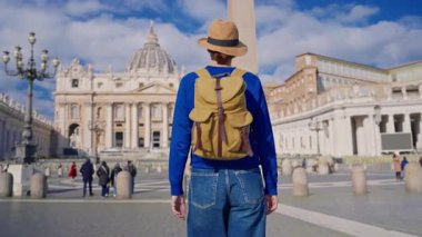 Şapkalı ve sırt çantalı bir turist kız Vatikan, Roma 'daki ikonik St. Peters Meydanı' na hayran..