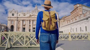 Şapkalı ve sırt çantalı bir turist kız Vatikan, Roma 'daki ikonik St. Peters Meydanı' na hayran..
