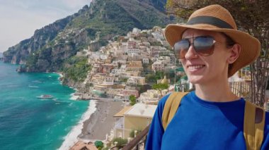 Şapkalı ve sırt çantalı bir kız turist Amalfi kıyısındaki ünlü İtalyan turist kasabası Positano 'nun güzelliğine hayran. İtalya. Yakın çekim..