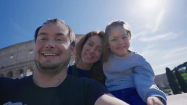 Roma 'da arka planda Colosseum' la fotoğraf çektiren ve kameraya gülümseyen bir aile. Roma, İtalya 'da turistler.