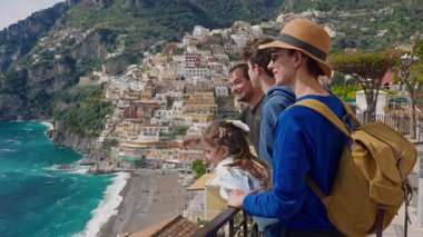 Amalfi Sahili 'nde tatilde olan dört kişilik bir aile, İtalya' nın ünlü turistik kasabası Positano 'nun manzarasının tadını çıkarıyor..