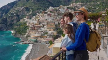 Amalfi Sahili 'nde tatilde olan dört kişilik bir aile, İtalya' nın ünlü turistik kasabası Positano 'nun manzarasının tadını çıkarıyor..