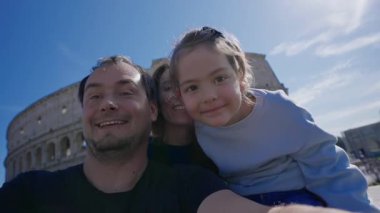 Roma 'da arka planda Colosseum' la fotoğraf çektiren ve kameraya gülümseyen bir aile. Roma, İtalya 'da turistler.