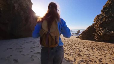 Sırt çantalı mutlu bir turist Ursa sahilinde yürüyor. Portekiz.