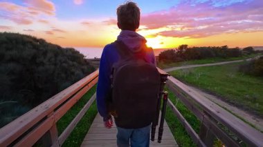 Sırt çantalı bir genç, Ponta de Piedad 'daki bir uçurumun kenarına okyanusun en güzel gün batımını görmeye gider, Portekiz..