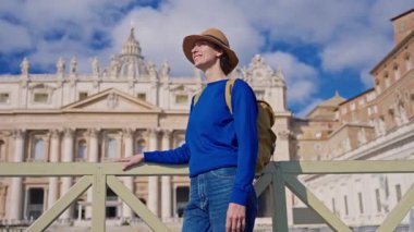 Şapkalı ve sırt çantalı bir turist kız Vatikan 'daki Aziz Peters Bazilikası' nın önünde duruyor..