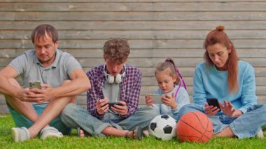 Küçük sevimli bir kız ve oğluyla dışarıda dinlenen mutlu bir aile. Aile açık havada akıllı telefon kullanıyor. Aile akıllı telefon bağımlılığı.