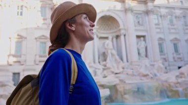 Şapkalı ve sırt çantalı bir kadın turist Trevi Çeşmesi 'nin önüne geliyor. Roma, İtalya 'yı gezen güzel kadın, 29.04.2025.